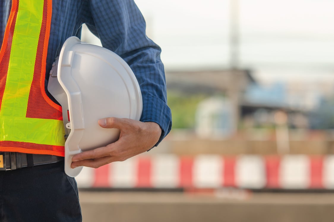 Construction site manager holding his hard hat. 